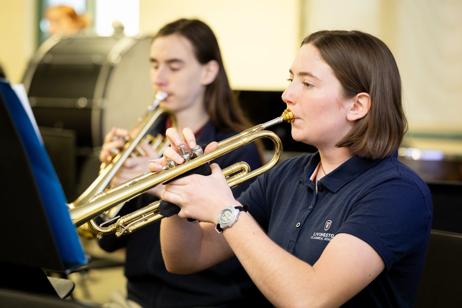 Young musicians rehearse together on trumpets, showcasing collaboration and artistry in a warm music room.