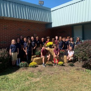 The 5th grade class poses outside of the school for a picture with the flowers they just planted.