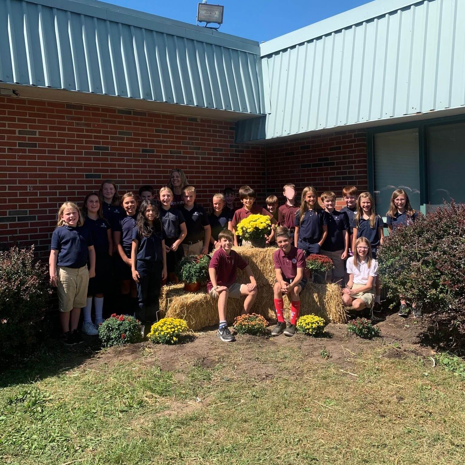 The 5th grade class poses outside of the school for a picture with the flowers they just planted.